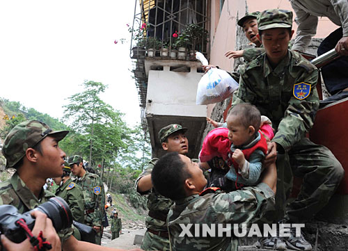 5月13日，在震后的北川縣城，武警戰(zhàn)士將一名和家人失散的幼童救出。 記者從四川省綿陽市抗震救災(zāi)指揮部了解到，受災(zāi)特別嚴重的北川縣老縣城80%、新縣城60%以上的建筑物因地震垮塌，縣城周邊發(fā)生大面積山體滑坡。