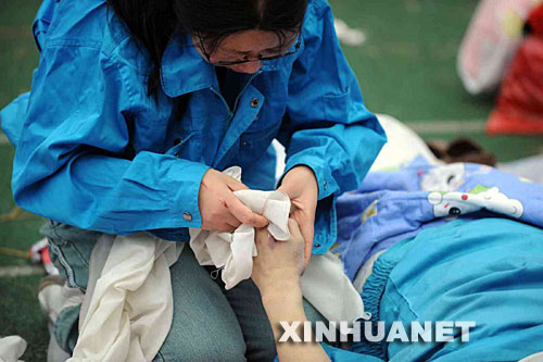 5月14日，張關(guān)蓉在擦拭丈夫譚千秋的遺體。 受汶川地震影響，四川省德陽市東汽中學(xué)教學(xué)樓坍塌。在地震發(fā)生的一瞬間，該校教導(dǎo)主任譚千秋雙臂張開趴在課桌上，身下死死地護(hù)著4個(gè)學(xué)生，4個(gè)學(xué)生都獲救了，譚老師卻不幸遇難。 新華社記者王建華攝