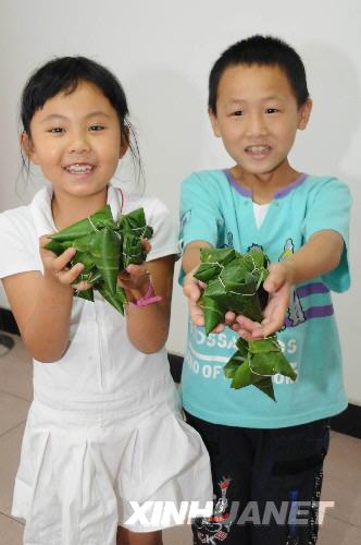  6月7日，來自地震災(zāi)區(qū)的呂雨童（左）和余俊鋒展示包好的粽子。 當(dāng)日，來自四川地震災(zāi)區(qū)的兩名二年級(jí)小學(xué)生呂雨童和余俊鋒，在湖北省宜昌市萬壽橋小學(xué)和新老師、新同學(xué)一起包粽子，迎端午。 