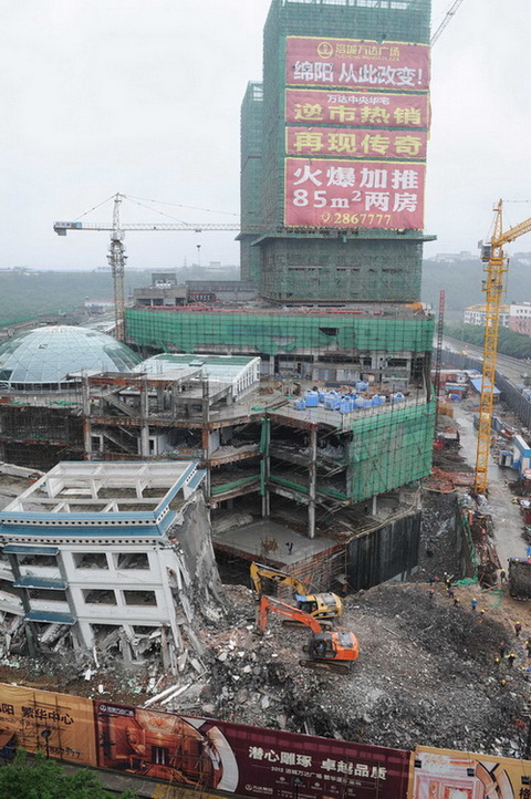 5月21日，工程機(jī)械在拆除綿陽紫荊民族中學(xué)校舍，旁邊則是建設(shè)中的萬達(dá)廣場。