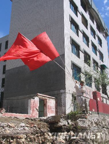  7月5日，一名防化兵高舉紅旗在北川縣城內(nèi)行走。當(dāng)日，記者經(jīng)特許進(jìn)入地震重災(zāi)區(qū)北川縣城采訪，用相機(jī)記錄下北川縣城的現(xiàn)狀。 